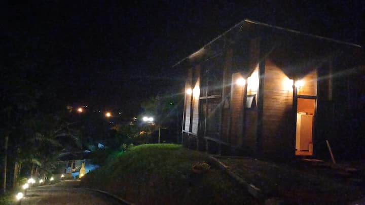 Fachada da cabana à noite com luzes acesas
